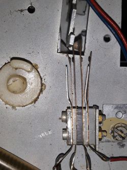 Zbliżenie na wnętrze urządzenia elektronicznego z widocznymi przewodami i elementami mechanicznymi.