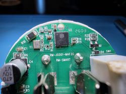 Close-up of a green PCB with an IC, SMD components, and “RM‑SMART” printed on the board.