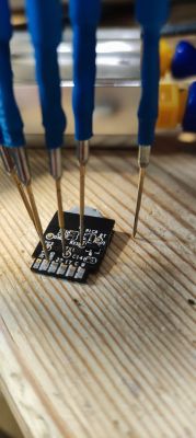Printed circuit board with connected test probes on a wooden surface.