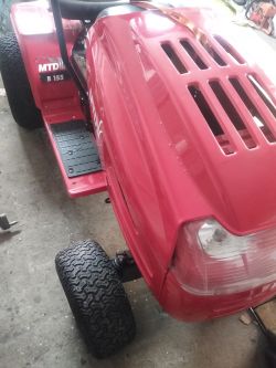Czerwony traktor kosiarka marki MTD model B 155 stojący w garażu.