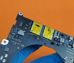 Płyta główna z komponentami SSD trzymana w ręku w rękawiczce.