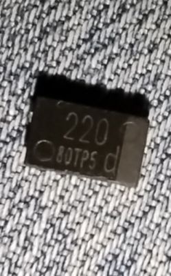 Mały czarny układ scalony z napisem „220 80TP5 d” na tle materiału dżinsowego