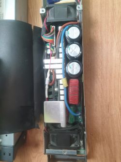 Wnętrze zasilacza z widocznymi komponentami elektronicznymi i przewodami.