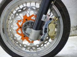 Przednie koło motocykla z tarczą hamulcową, zaciskiem Brembo i zamontowanym czujnikiem.
