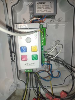 Panel sterowania automatyki bramy przemysłowej z widocznym okablowaniem i przyciskami.