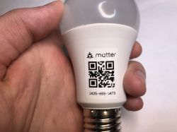Image of an LED bulb held in hands with a QR code and serial number.