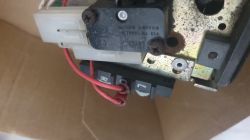 Zbliżenie na części mechanizmu z mikroprzełącznikiem i czerwonymi kablami.