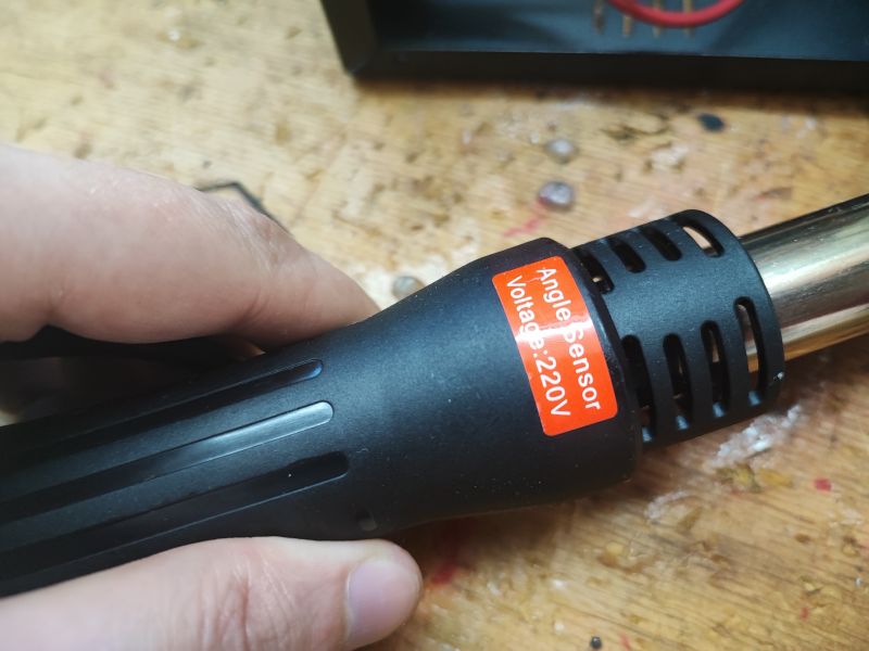 Hot Air Soldering Iron with Angle Sensor Close-up of a black hot air soldering iron with a sticker labeled Angle Sensor Voltage 220V.