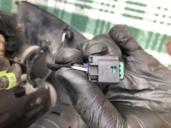 Czarny wtyk elektryczny trzymany w ręku w gumowej rękawicy