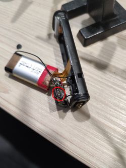 Interior of a disassembled electronic cigarette showing the battery and the puff sensor, marked in red.