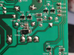 Close-up of a green printed circuit board with electronic component markings.