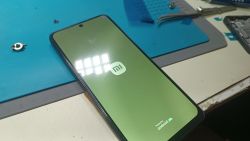 Telefon z zielonym odcieniem na ekranie OLED podczas uruchamiania systemu