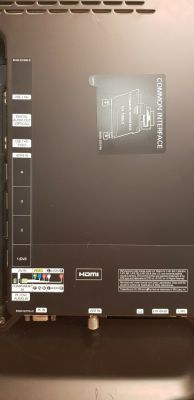 Tył telewizora z naklejką „COMMON INTERFACE” i różnymi portami.