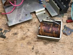 Electromagnet coil in a metal frame on a wooden workbench, with metal plates and wires nearby.