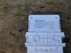 Back of Sonoff POWR316D module with technical details on a wooden background.