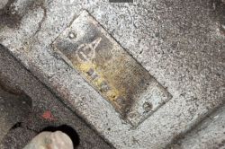 Zbliżenie na metalową tabliczkę znamionową na chropowatej, zabrudzonej obudowie