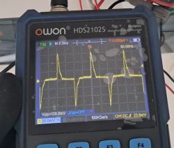 Ekran przenośnego oscyloskopu OWON HDS2102S z żółtym przebiegiem impulsowym ok. 50 Hz