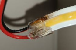 Zbliżenie na przewody elektryczne połączone w sposób prowizoryczny klejem.