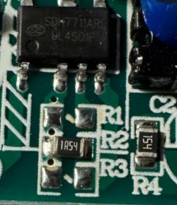 Zbliżenie PCB z układem scalonym i rezystorem SMD oznaczonym „1R54” obok pól R1–R4