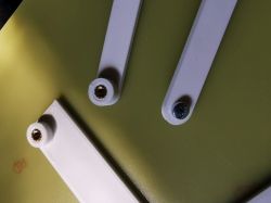 Close-up of a white mounting jig with three arms screwed into a green surface.