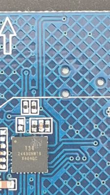 Close-up of a blue PCB with integrated circuit, SMD parts, and conductive traces