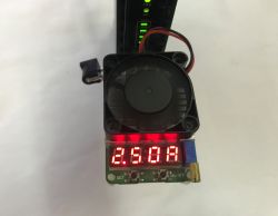 Electronic load with fan and red LED readout “2.50A” connected to a UPS in the background