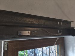 Zamontowany kontaktron Satel B-3 na metalowej szynie nad ramą drzwi