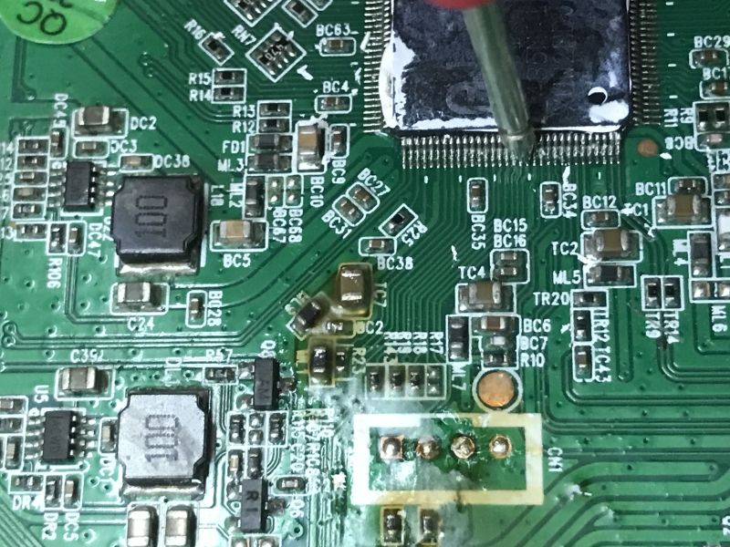 Close-up of a probe touching IC pins on a DVB tuner printed circuit board.