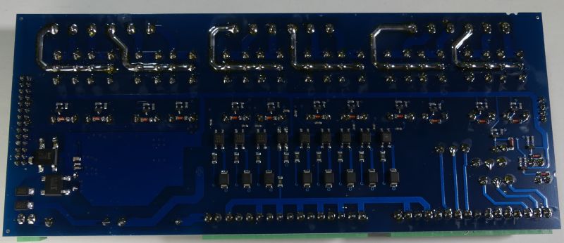 Spód niebieskiej płytki PCB z licznymi lutami, ścieżkami i elementami SMD