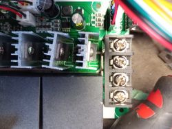 Zbliżenie na płytkę elektroniczną z widocznymi radiatorem, złączem i uszkodzoną diodą.