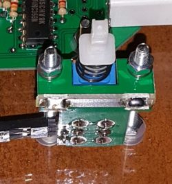 Zbliżenie na płytkę drukowaną z przyciskiem isostat i elementami elektronicznymi.