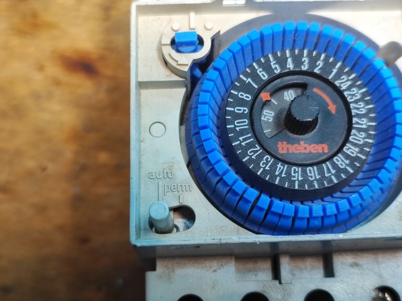 Zbliżenie na mechaniczny programator czasowy Theben z niebieskimi segmentami do ustawiania czasu.