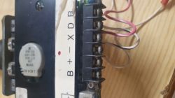 Obraz przedstawia zbliżenie panelu elektronicznego z kilkoma przewodami podłączonymi do zacisków oznaczonych literami B, X, D, R na płycie.