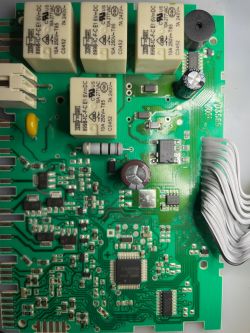 Zbliżenie na płytkę drukowaną z komponentami elektronicznymi, w tym przekaźnikami i diodą SR53.