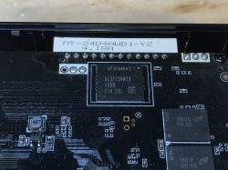 Zbliżenie na płytę główną przystawki TV z widocznymi układami pamięci i elementami elektronicznymi.