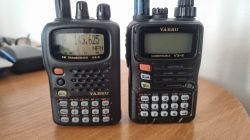 Dwa ręczne radiotelefony Yaesu obok siebie na drewnianym blacie, z antenami u góry