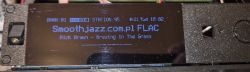 OLED display in a dark plexiglass case showing SmoothJazz.com.pl station