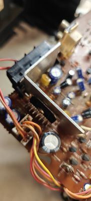 Zbliżenie na naprawioną płytkę elektroniczną z widocznymi kondensatorami i przewodami.