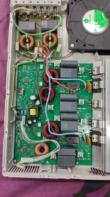 Wnętrze płyty indukcyjnej z widocznymi elementami elektronicznymi, w tym tranzystorami i cewkami.