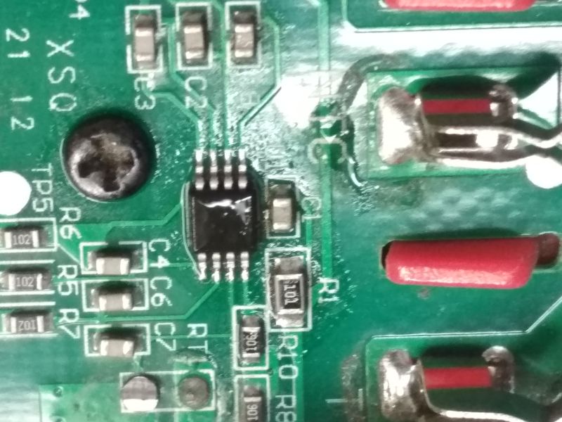 Zbliżenie na fragment płytki drukowanej z elementami elektronicznymi oraz śrubą krzyżakową.
