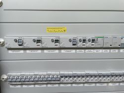 Panel elektryczny z różnymi włącznikami i bezpiecznikami oznaczonymi etykietami Dymo.