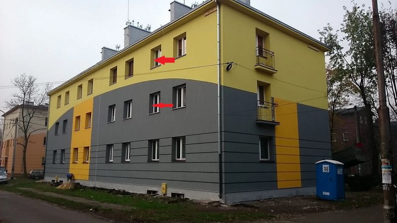 Residential building with colorful facade, with two windows marked with arrows.