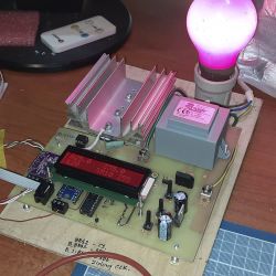 Płytka elektroniczna z podzespołami i świecącą różową żarówką.