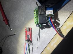 Two electronic modules connected with colored wires on a metal work surface.