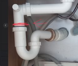 Instalacja syfonu z karbowanym wężem, ze strzałką i oznaczeniem miejsca do przycięcia