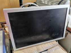Stary monitor LCD z szarą ramką ustawiony na kartonie.