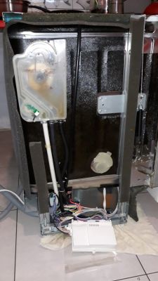 Widok z tyłu rozebranej zmywarki z widoczną instalacją hydrauliczną i elektryczną.