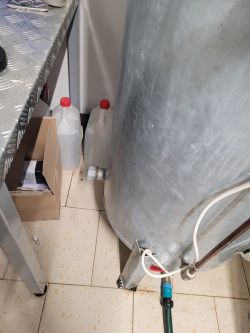 Hydrofor ciśnieniowy z rurką i pojemnikami na wodę w pomieszczeniu gospodarczym.