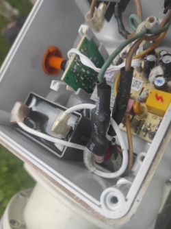 Widok na wnętrze obudowy elektrycznej z przewodami podłączonymi do różnych komponentów.