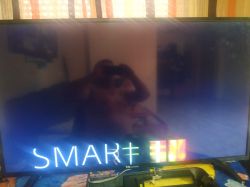 A television with the SMART logo displayed on the screen, showing the reflection of the photographer.